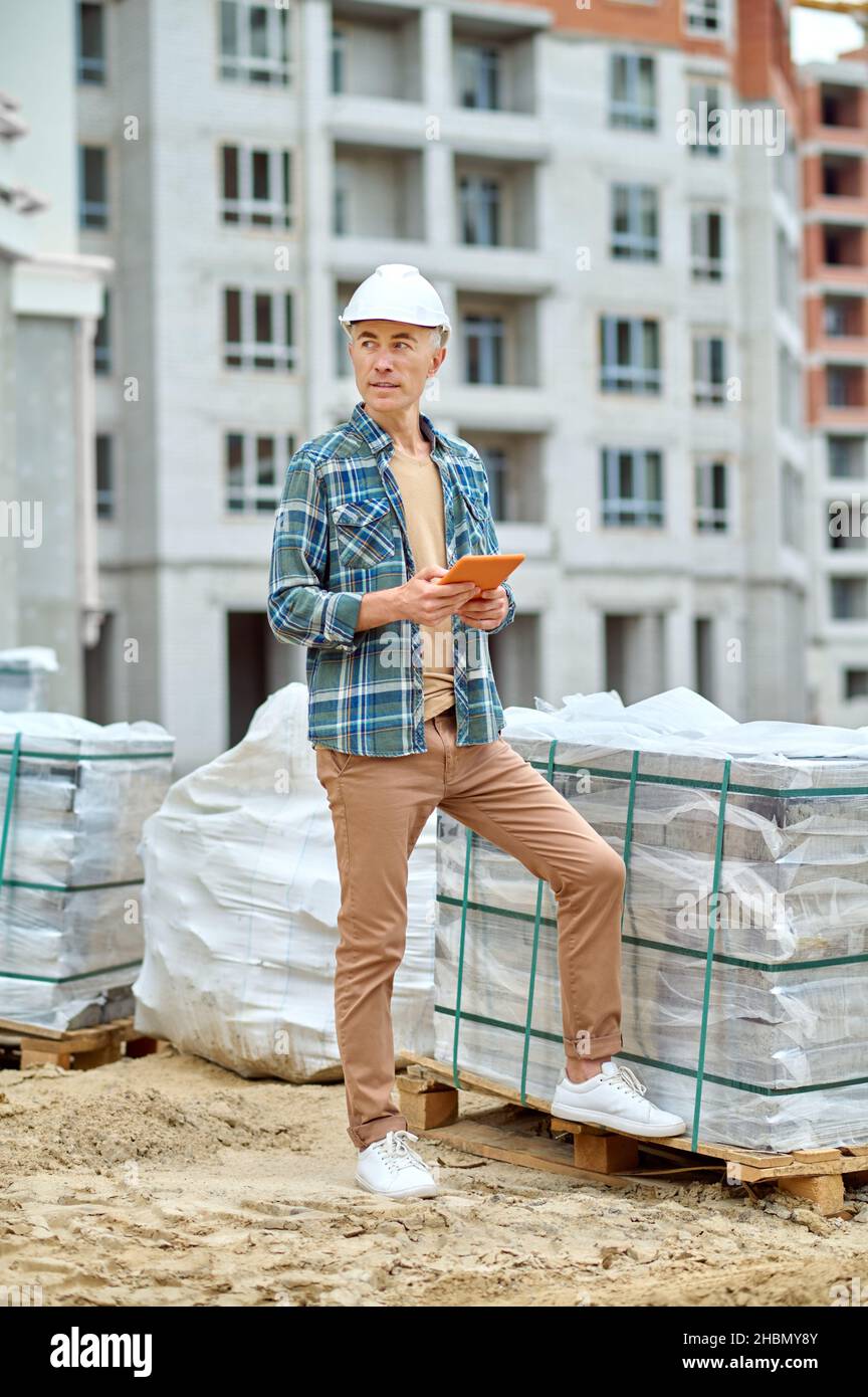 Hombre parado en el sitio de la construcción mirando a un lado Foto de stock