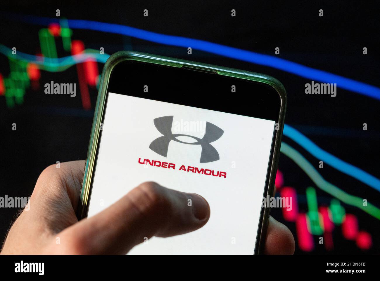 En esta ilustración de la foto, la marca de ropa multinacional  estadounidense con el logotipo de Armor aparece en un smartphone con un  gráfico del índice de la bolsa de valores económica