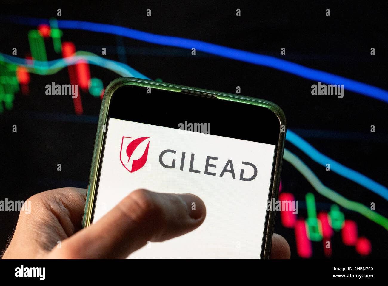 En esta ilustración de la foto se muestra el logotipo de la empresa  estadounidense de biotecnología Gilead Sciences en un smartphone con un  gráfico del índice de la bolsa de valores económica