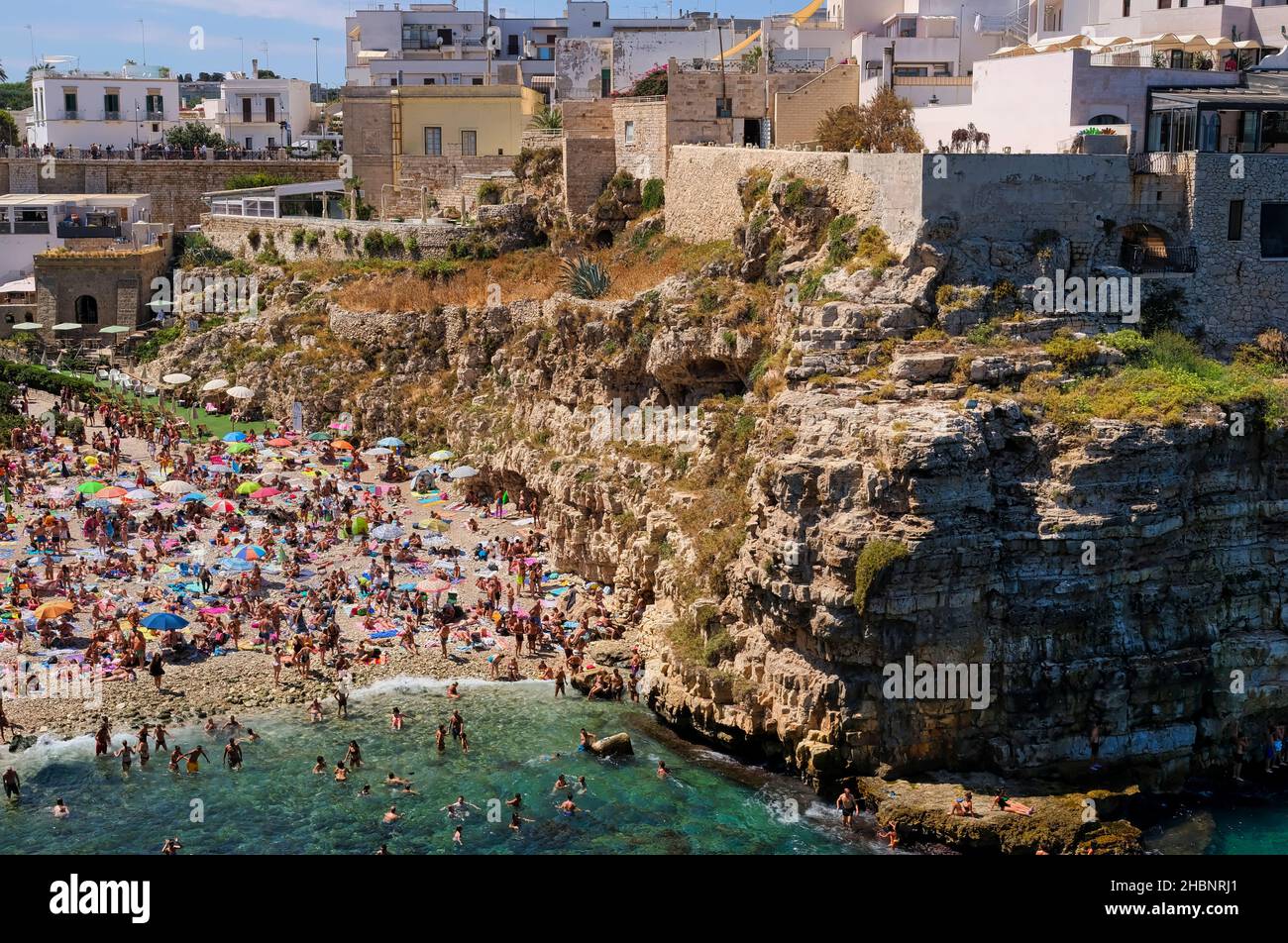 Polignano a Mare, sur de Italia provincia de Bari - famosa playa Lama Monachile entre escarpados acantilados y edificios blancos Foto de stock