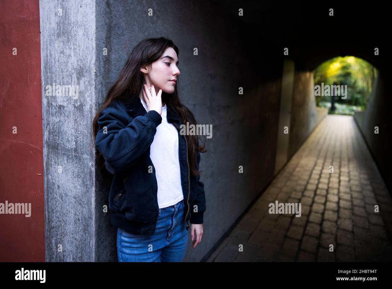 Mujer caucásica adolescente en vaquero de pie en la entrada del túnel peatonal Foto de stock