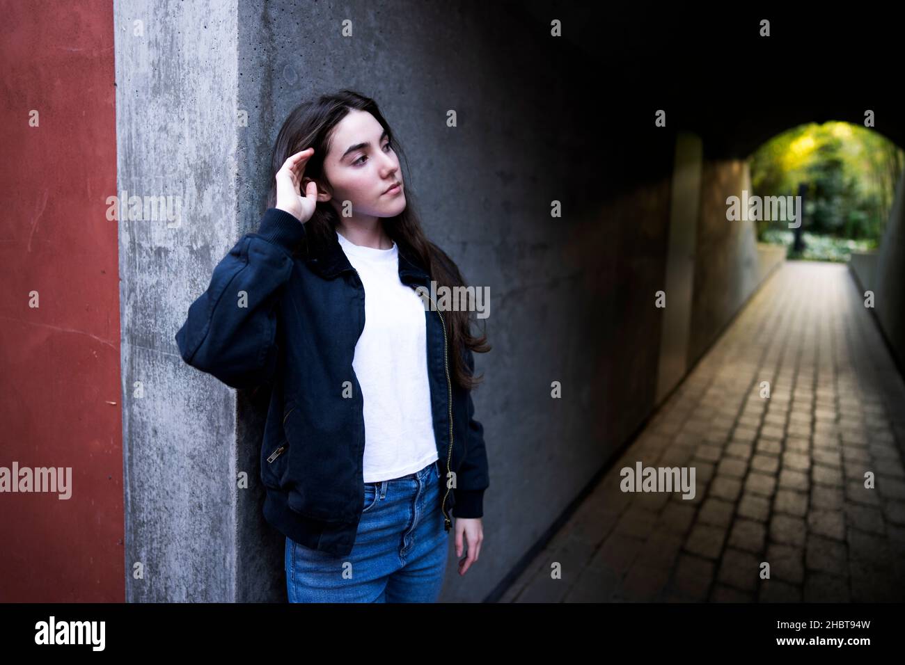 Mujer caucásica adolescente en vaquero de pie en la entrada del túnel peatonal Foto de stock