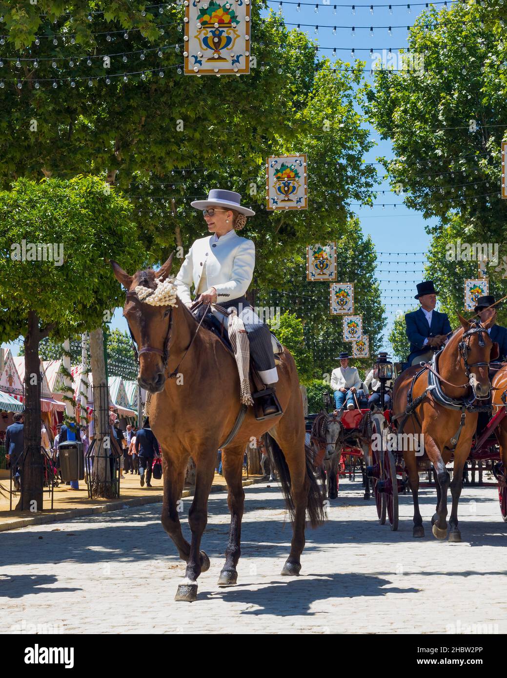 Sevilla, provincia de Sevilla, Andalucía, sur de España. Feria de Abril. Desfile de caballos y carruajes. Mujer madura jinete en tradicional Foto de stock