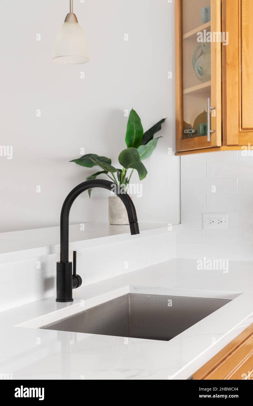Un detalle de fregadero de la cocina con encimera de mármol blanco, grifo  negro y armarios de madera Fotografía de stock - Alamy