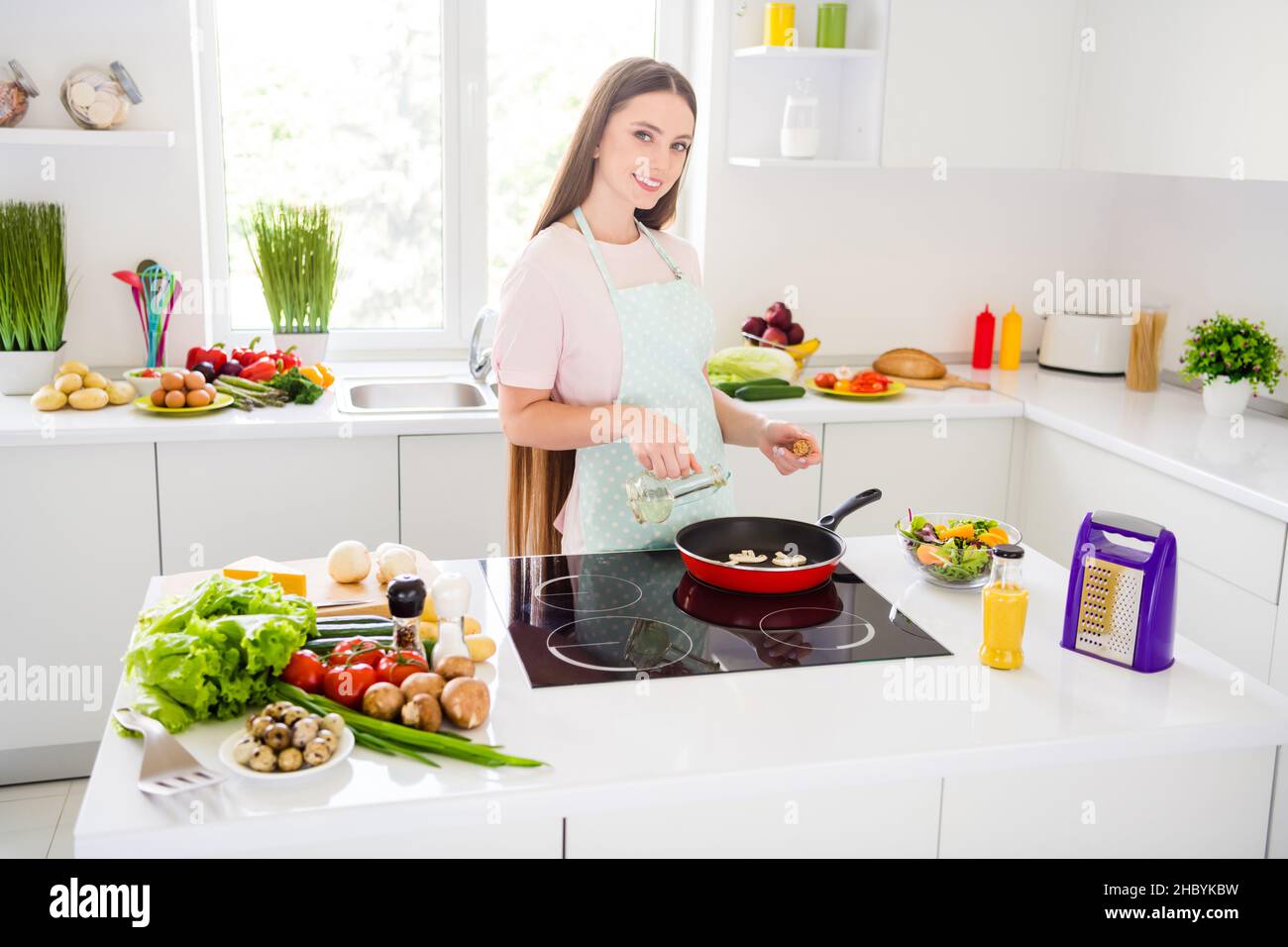 Retrato de una chica atractiva y alegre cocina sabrosa deliciosa comida casera gourment freír la cena en blanco claro cocina en casa interior Foto de stock