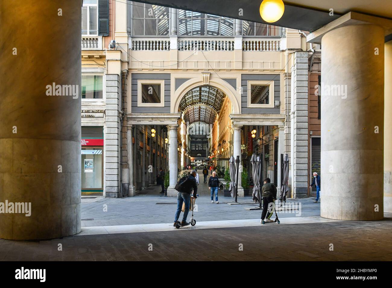 Gente caminando y en motonetas bajo la galería Giuseppe Siri (Teatro Carlo Felice) y Galleria Giuseppe Mazzini, Génova, Liguria, Italia Foto de stock