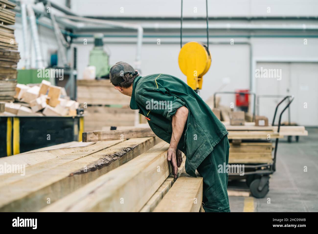 Trabajador de carpintería en fábrica con pila de madera. Foto de stock