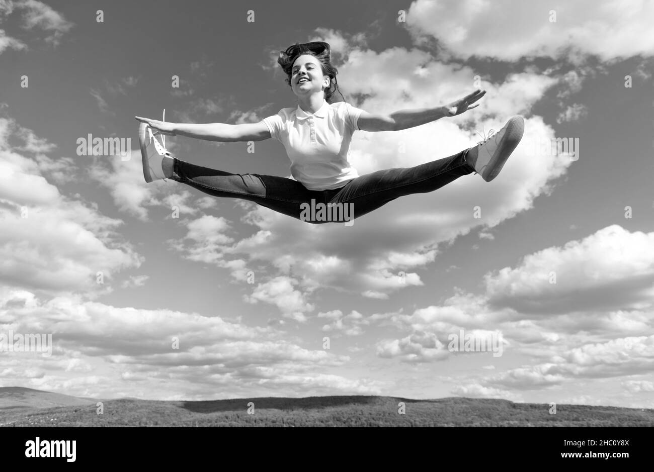 lleno de energía. calentamiento de la gimnasta sobre el fondo del cielo. flexibilidad. Foto de stock