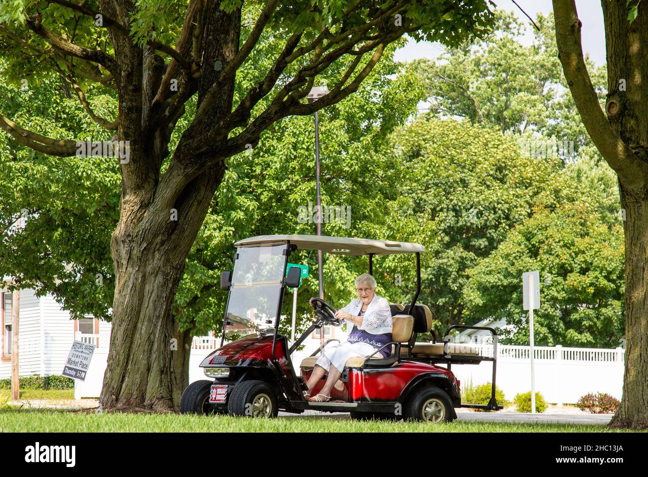 Una mujer mayor conduce su carro de golf EZ-Go entre los árboles en Riverside Gardens Park en Warren, Indiana, Estados Unidos. Foto de stock