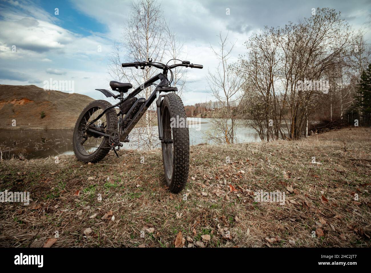Una gran bicicleta negra en la orilla del lago. Pasatiempo deportivo saludable. Foto de stock