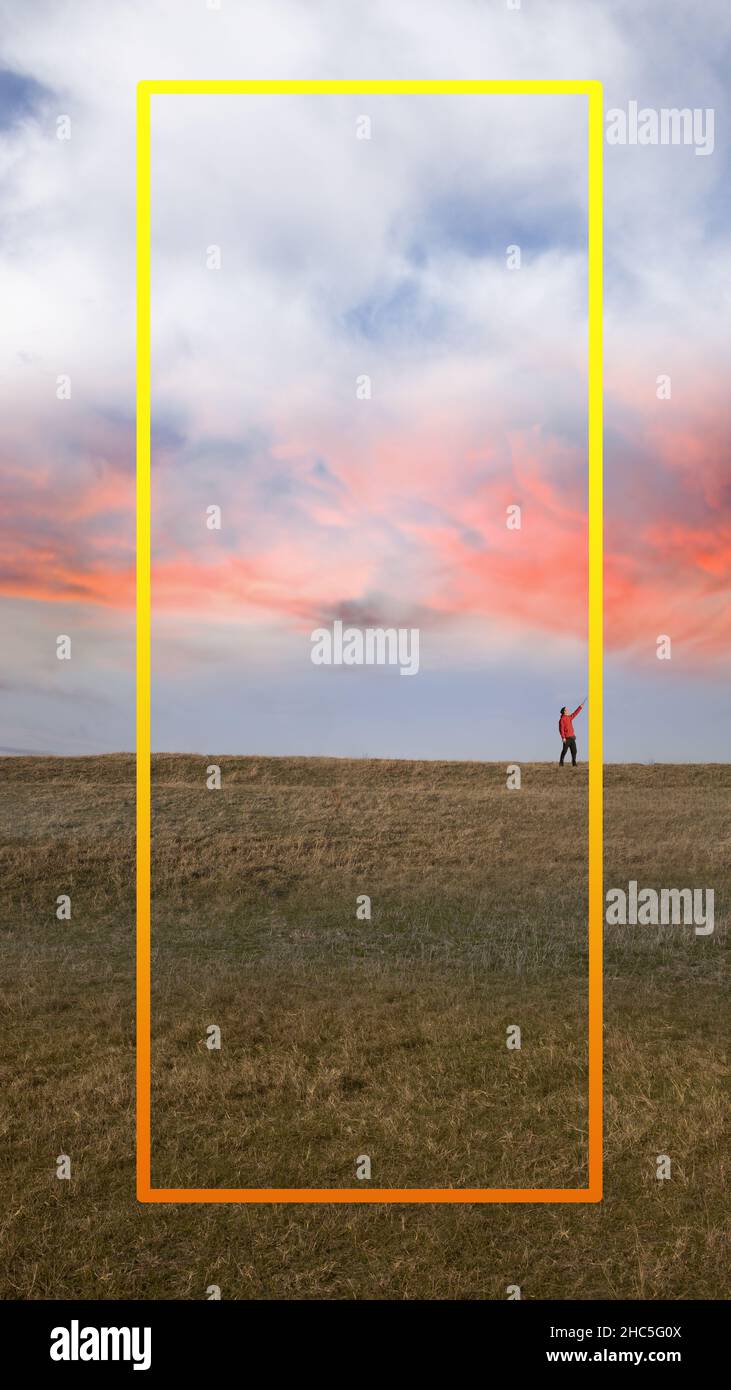 Un hombre apuntando al cuadro de texto amarillo durante una hermosa puesta de sol. Optimizado para un teléfono móvil. Foto de stock