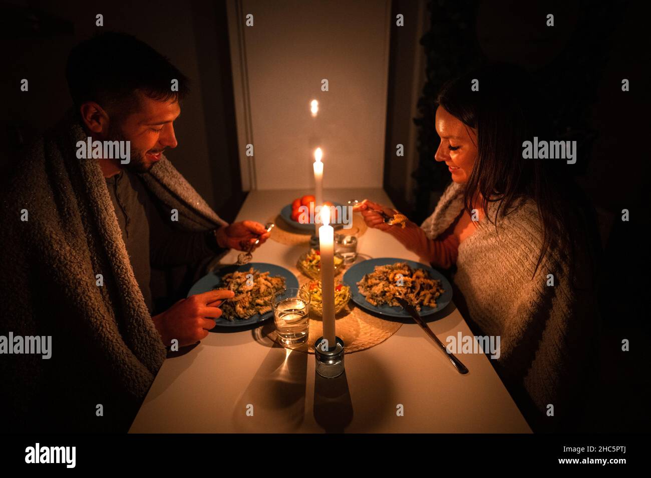 Pareja cenando en casa durante un corte de electricidad. Cortinas opacas, no hay electricidad Foto de stock