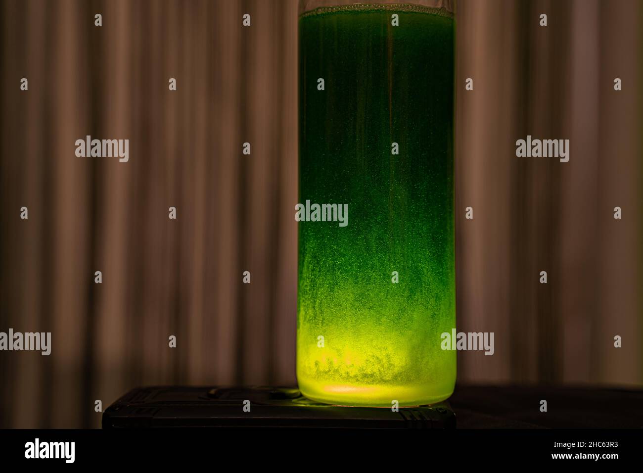 Cristal con líquido verde iluminado con luz amarilla Foto de stock