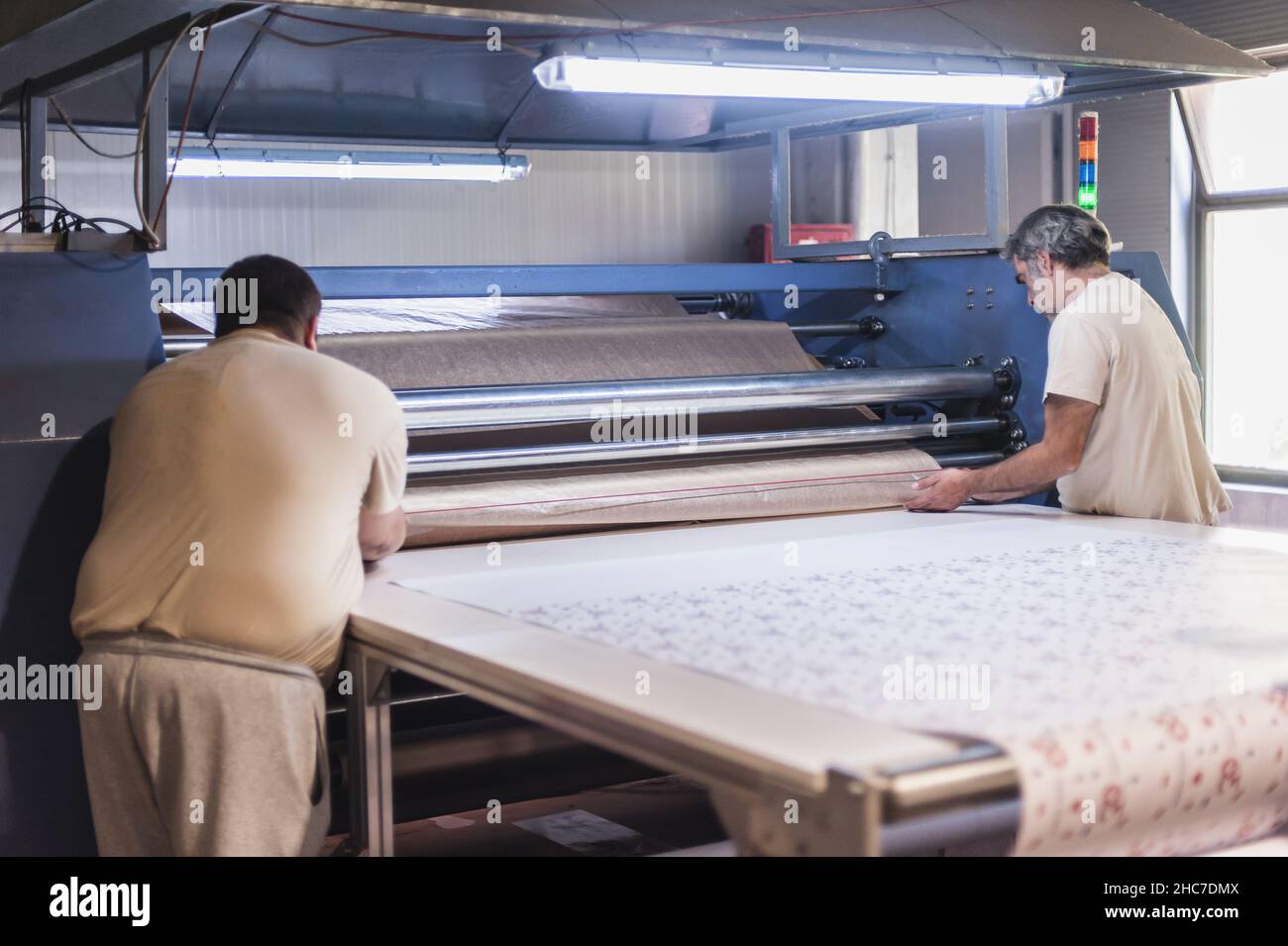 Dos técnicos trabajadores operador trabaja en tela de primera calidad industrial de sublimación rodillo de impresión por calor en la imprenta digital o Foto de stock