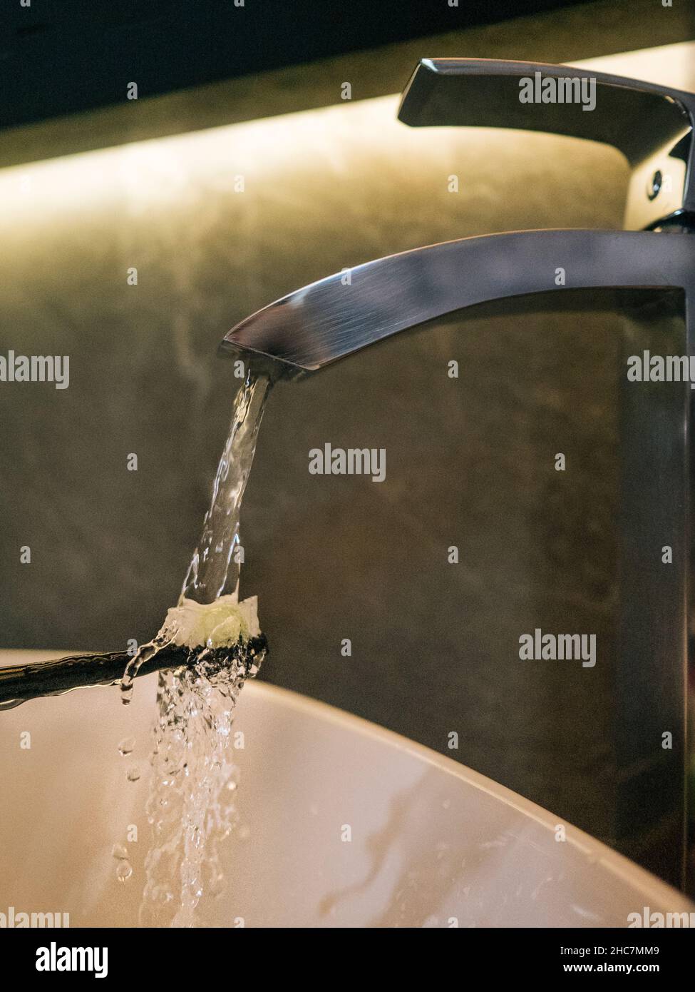 Cepillo de dientes bajo el agua corriente de un grifo de acero Foto de stock
