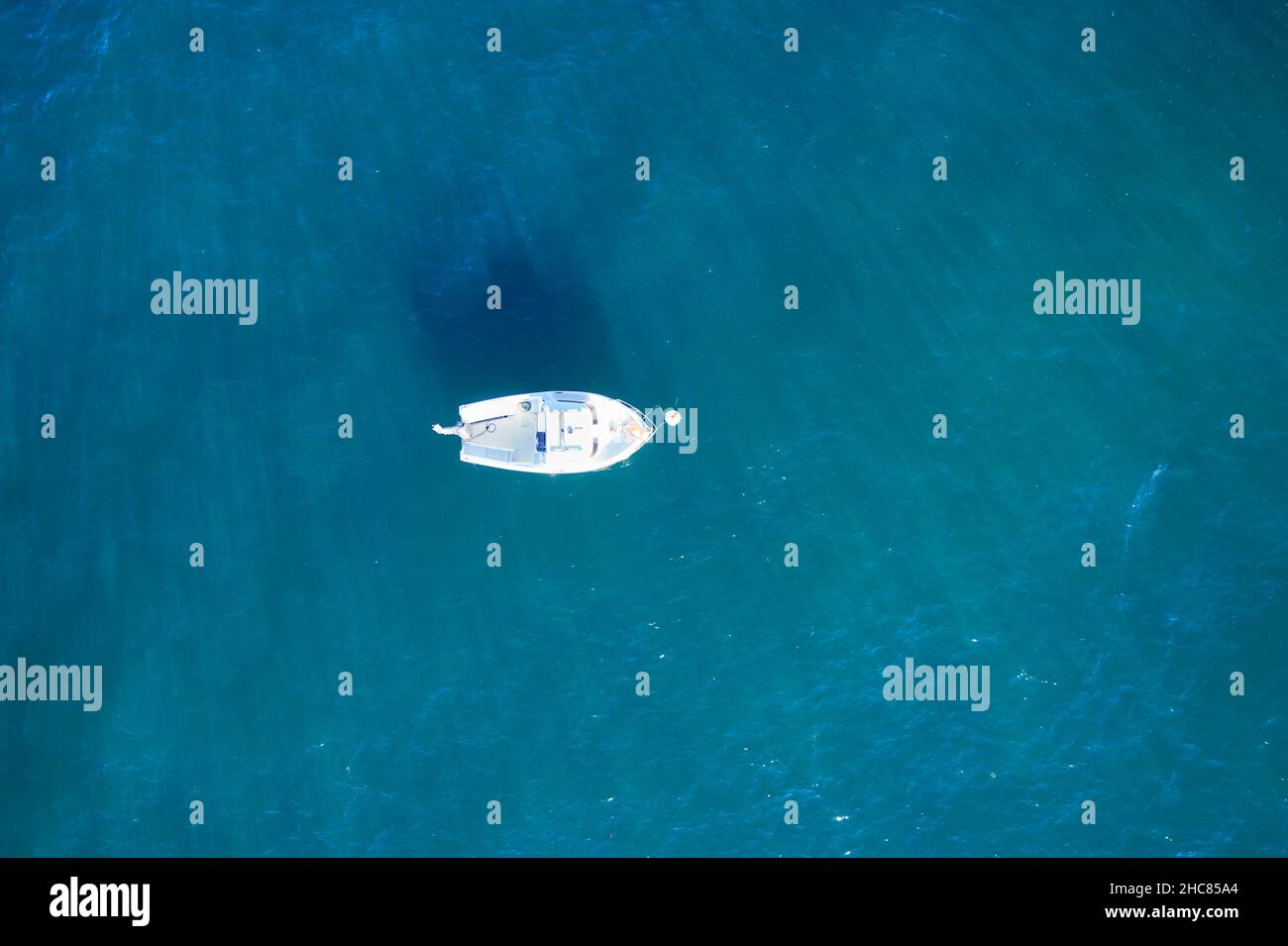 Barco de pesca vacío desde arriba en el atlántico. Vista aérea de un pequeño barco blanco sobre el agua azul del mar. Objeto aislado. Foto de stock