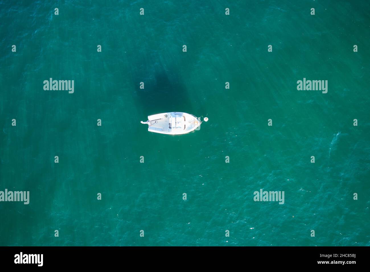 Barco de pesca vacío desde arriba en el atlántico. Vista aérea de un pequeño buque blanco sobre agua verde azul. Objeto aislado. Foto de stock
