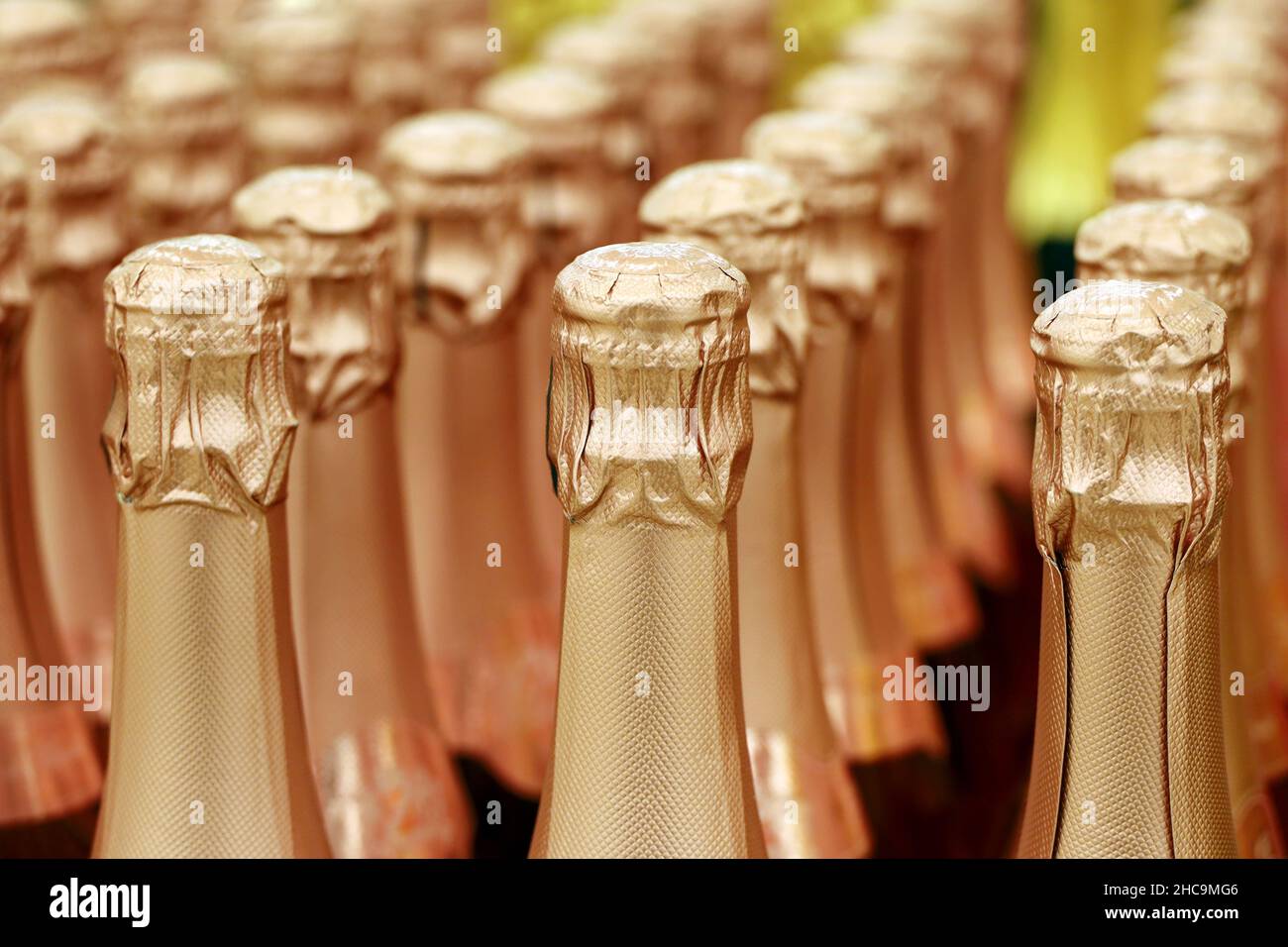 Botellas de vino espumoso en papel de aluminio dorado para la celebración de Año Nuevo. Champán en la tienda de vinos, industria del alcohol Foto de stock