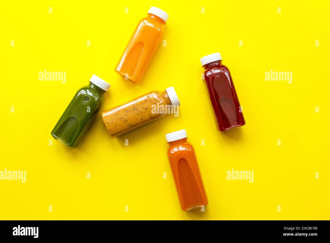 Zumos frescos o cócteles de frutas y verduras en botellas sobre fondo amarillo. El concepto de una dieta o dieta saludable. Ingredientes orgánicos frescos Foto de stock