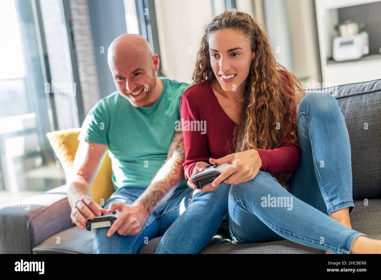 Pareja sonriente con el mando de videojuegos jugando en el sofá Foto de stock