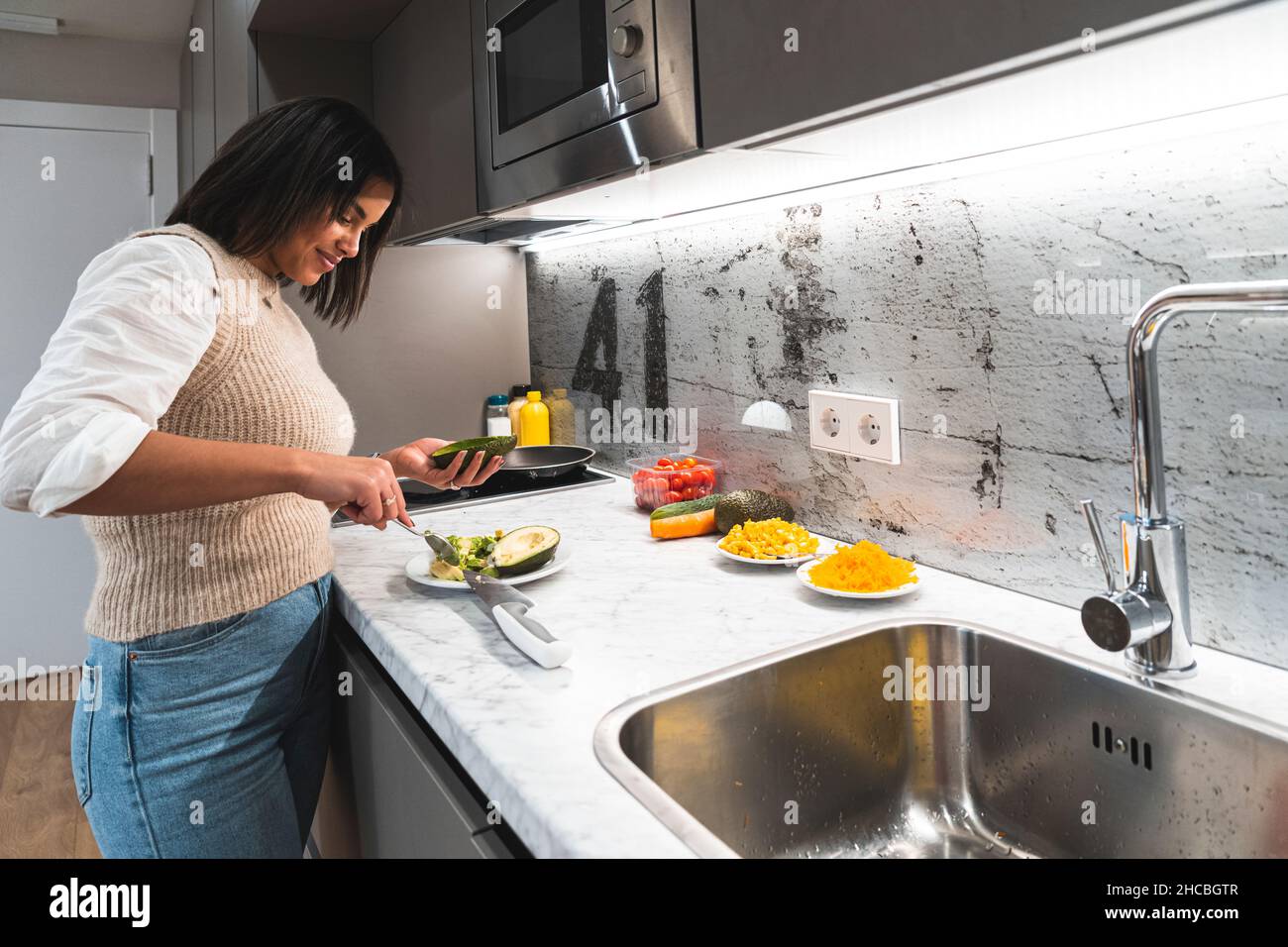 Mujer cortando aguacate con cuchillo de cocina en casa Foto de stock