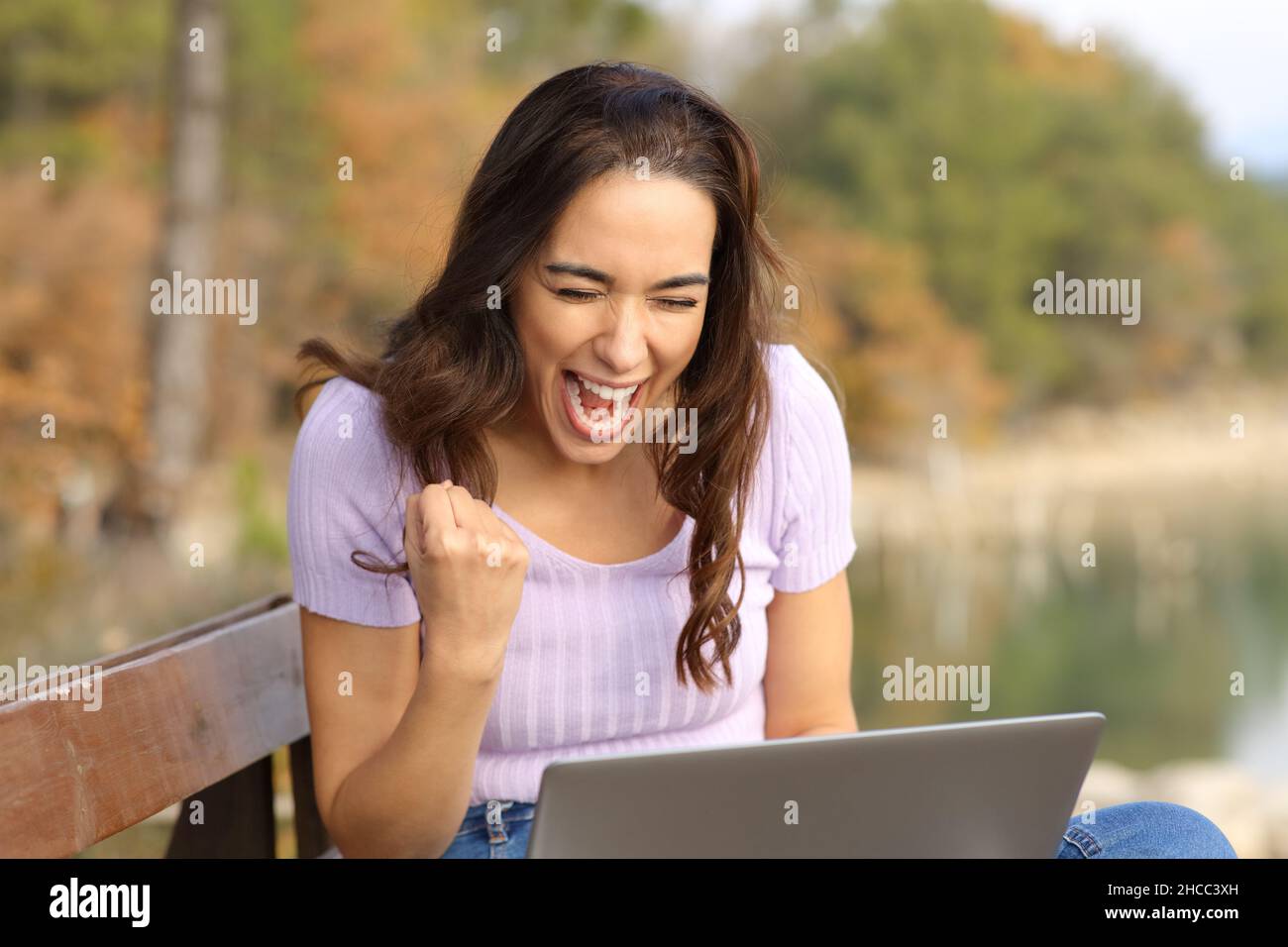 Mujer emocionada con un portátil que celebra el éxito en la montaña Foto de stock