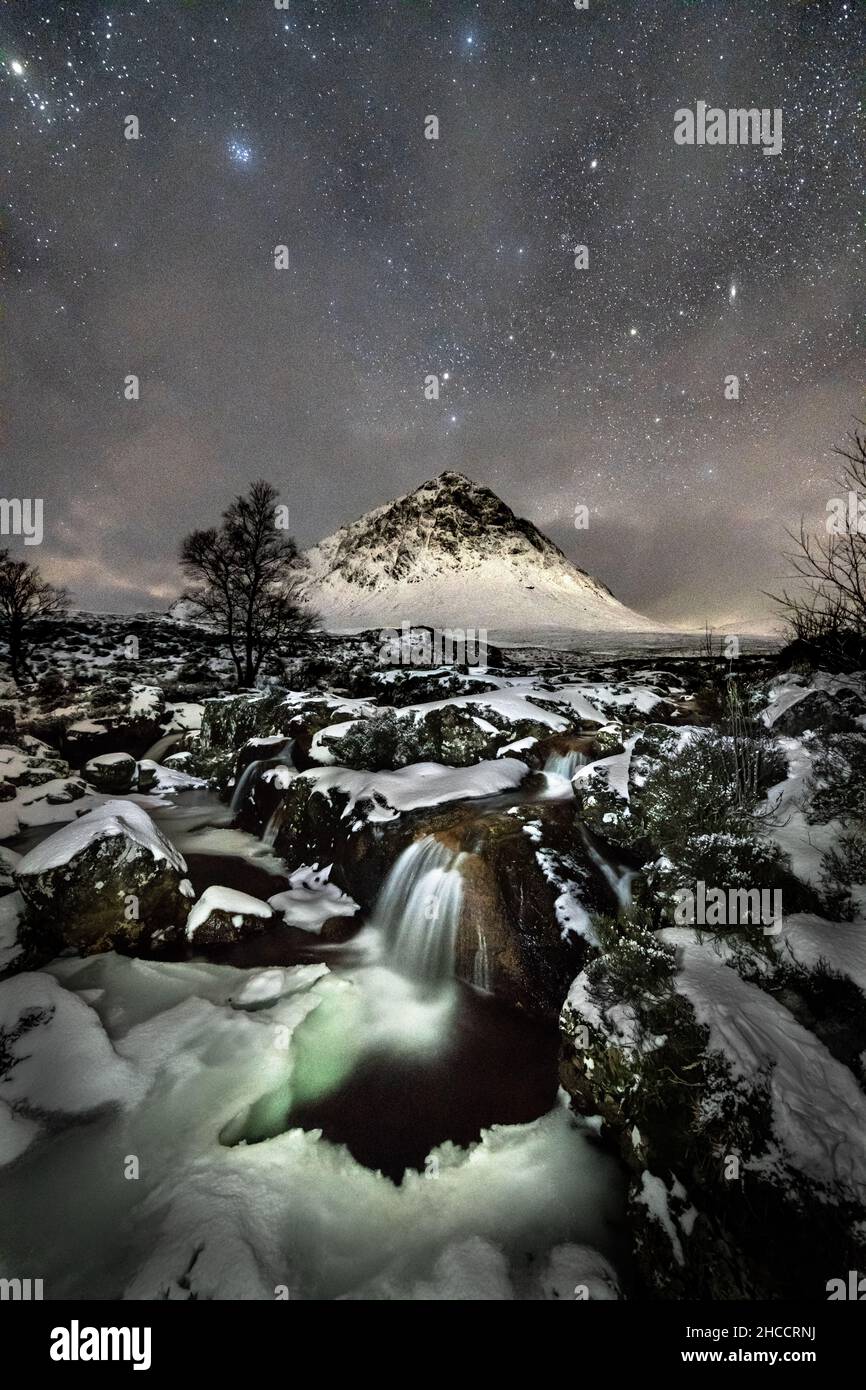 Stob Dearg (el pico más prominente de Buachaille Etive), el río Coupall y el cielo nocturno en un día de invierno en Glencoe, Escocia, Reino Unido. Foto de stock