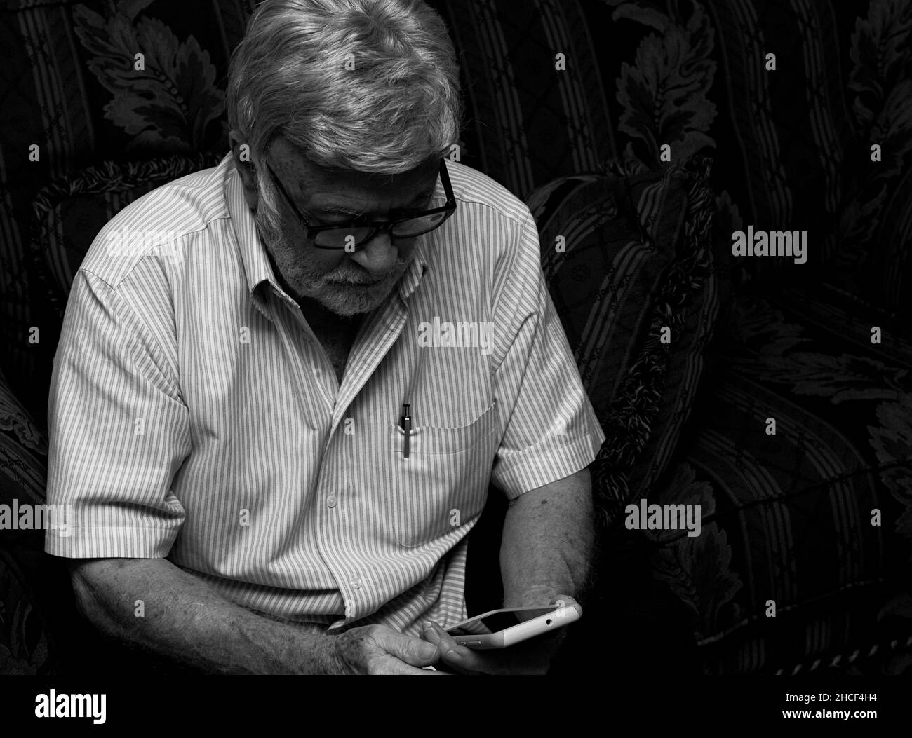 Foto en blanco y negro de un viejo hombre que se ensucia con un teléfono Foto de stock