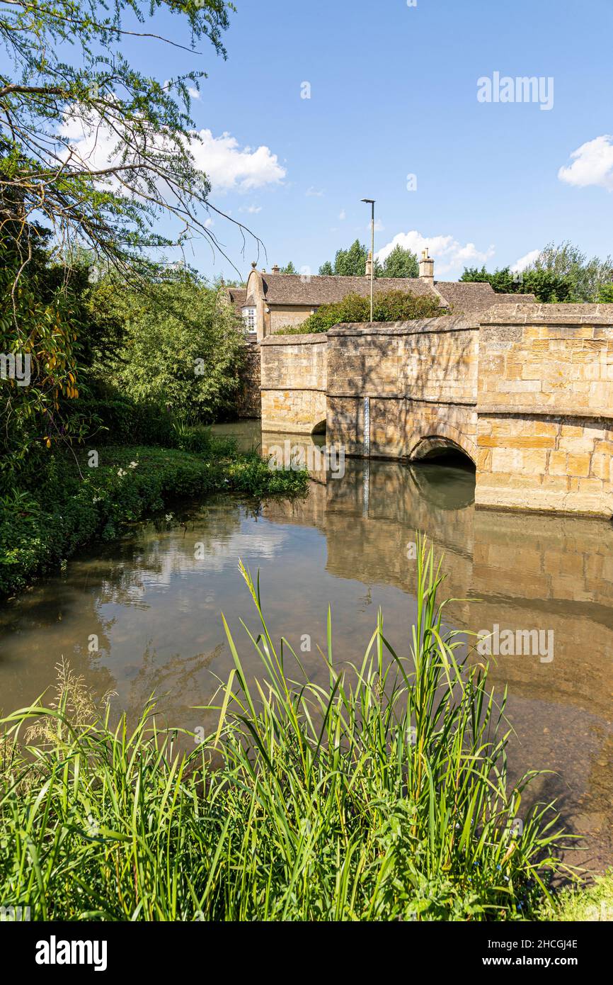 El río Windrush fluye bajo el antiguo puente de piedra en la ciudad de Cotswold Burford, Oxfordshire, REINO UNIDO Foto de stock