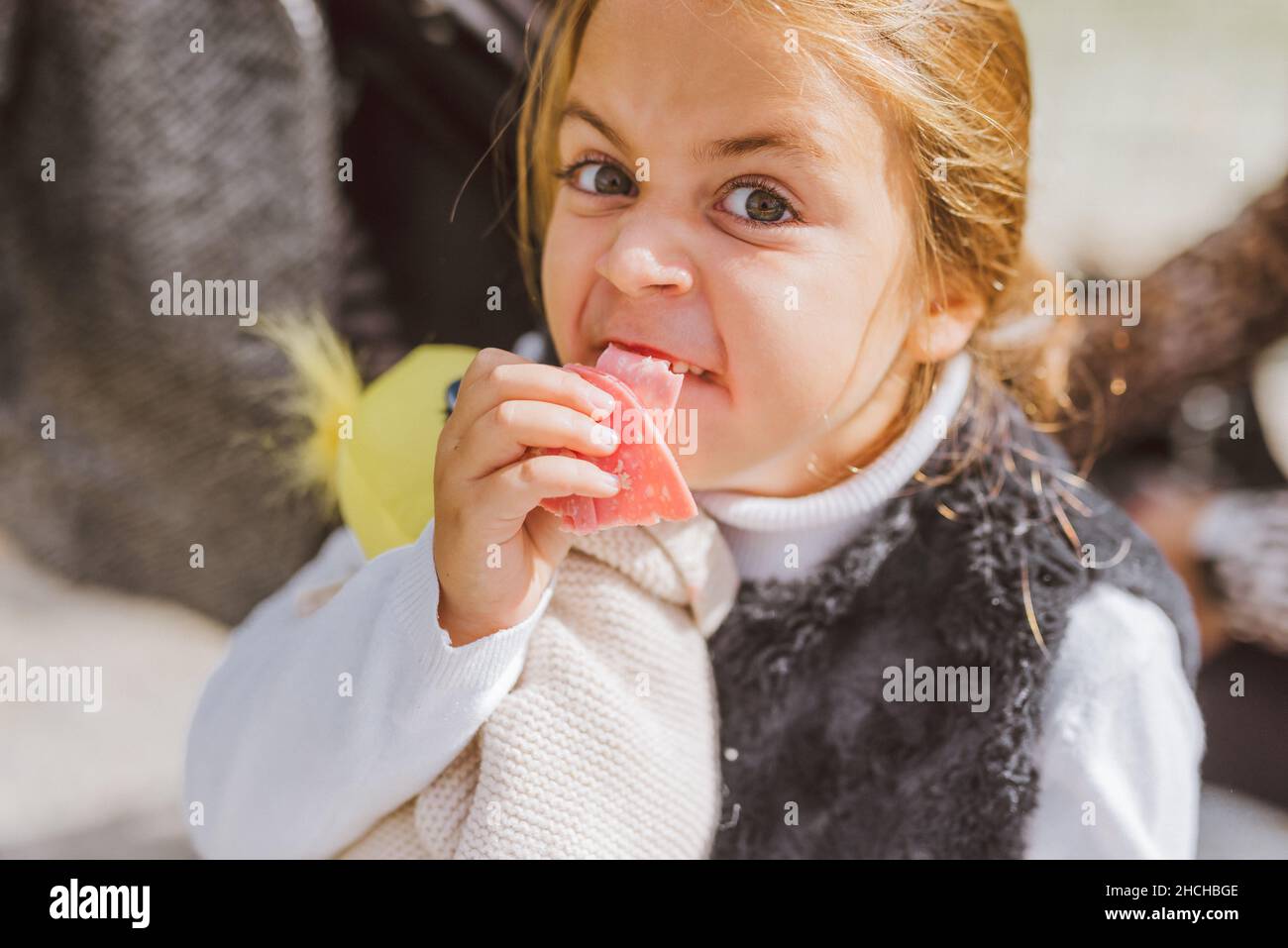 Chica caucásica haciendo una cara fea mientras come bolonia. Foto de stock