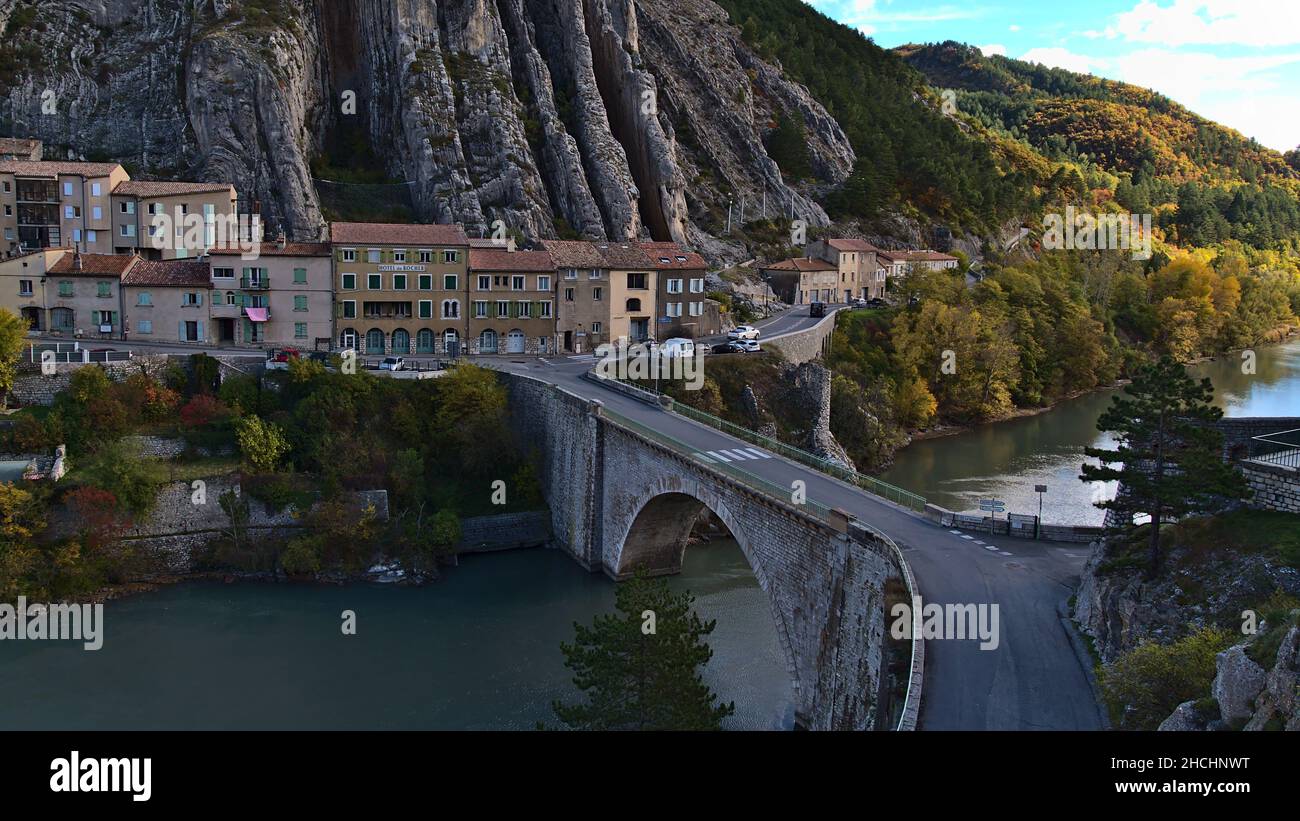 Vista del río Durance en el pueblo de Sisteron, Provenza, Francia en la temporada de otoño con el famoso puente Pont de la Baume y coloridos árboles. Foto de stock