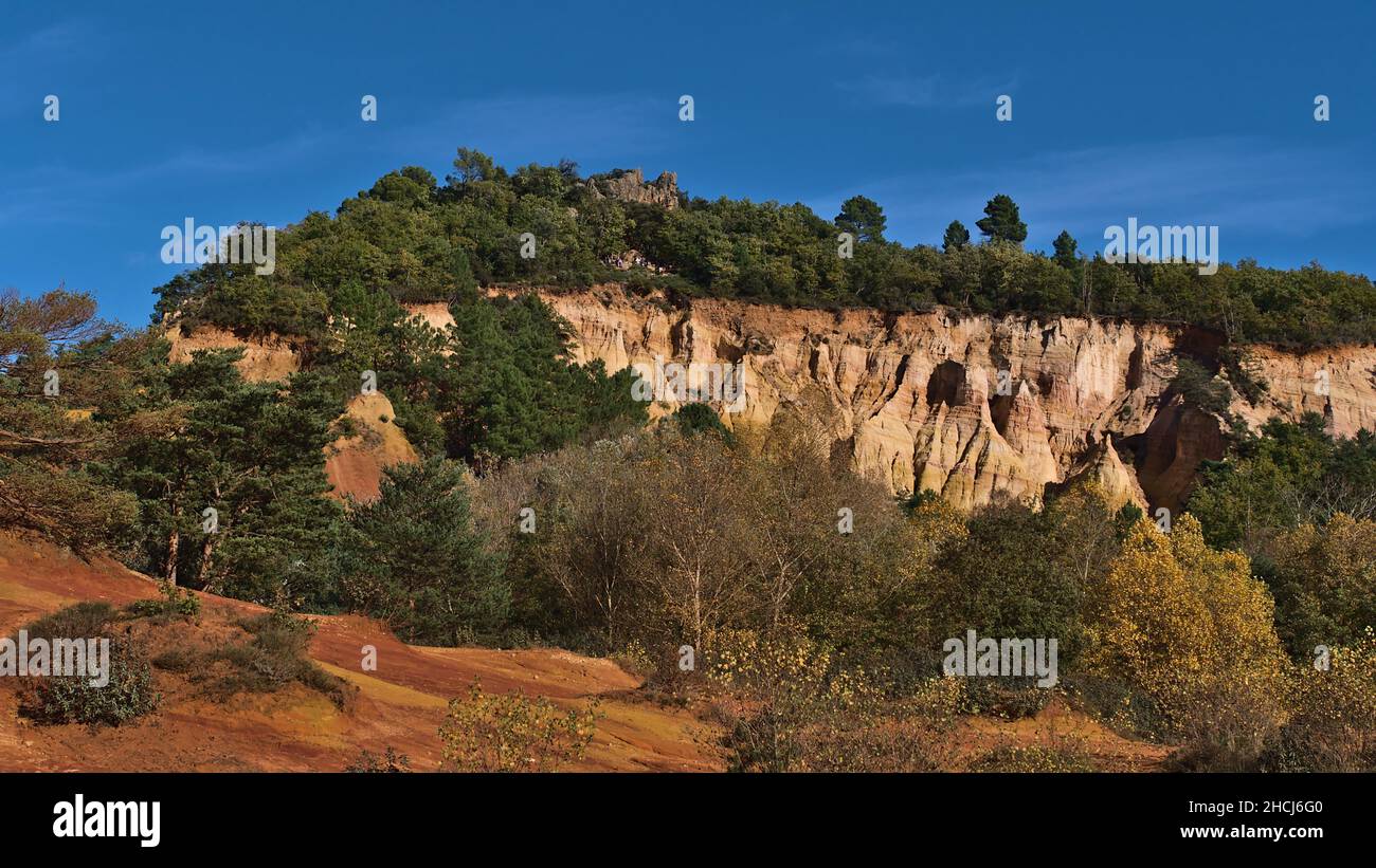 Impresionantes vistas de formaciones rocosas de varios colores ocre con colores naranja y amarillo en Colorado Provencal cerca de Rustrel en Provenza, Francia en el día soleado. Foto de stock