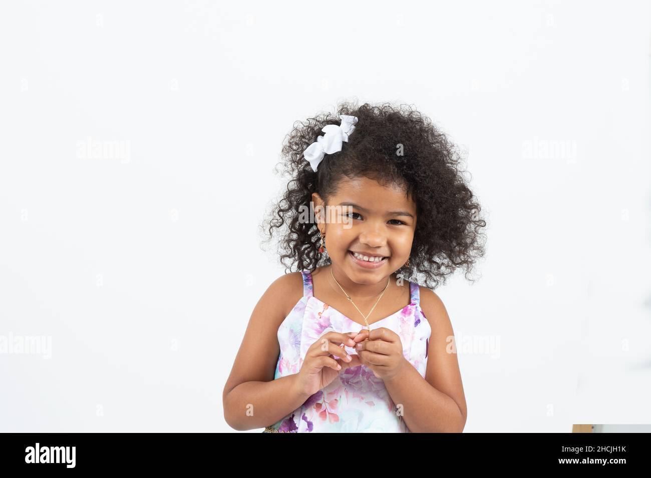 Primer plano retrato de una niña de 4 o 5 años, sonriente, fondo blanco Foto de stock