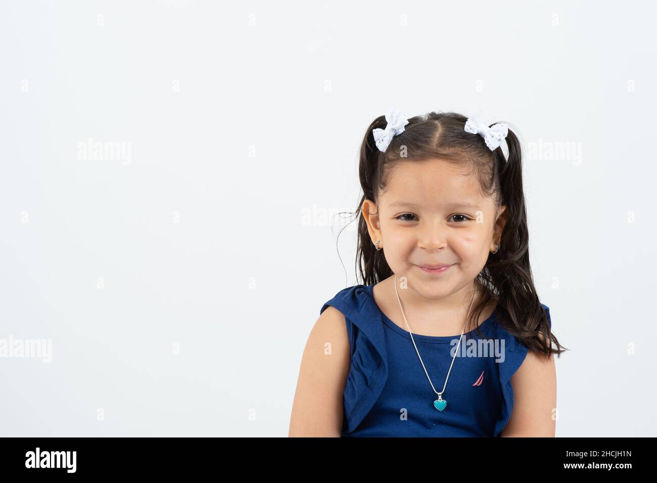 Primer plano retrato de una niña de 4 o 5 años, sonriente, fondo blanco Foto de stock