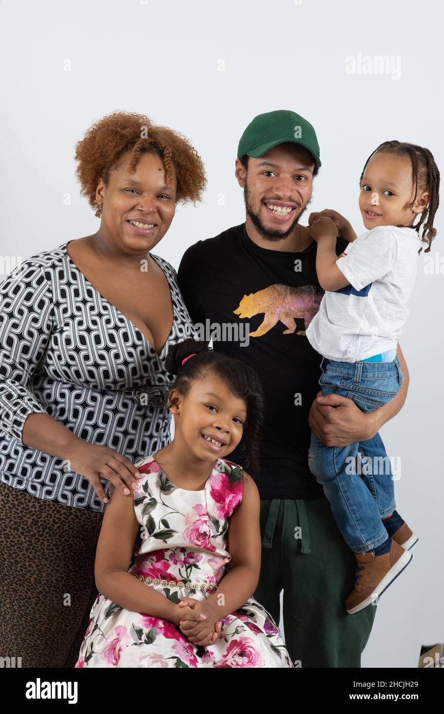 Retrato de primer plano de una niña de 4 o 5 años, a fuego lento, con madre, padre y hermano de 3 años, retrato de familia sobre fondo blanco Foto de stock