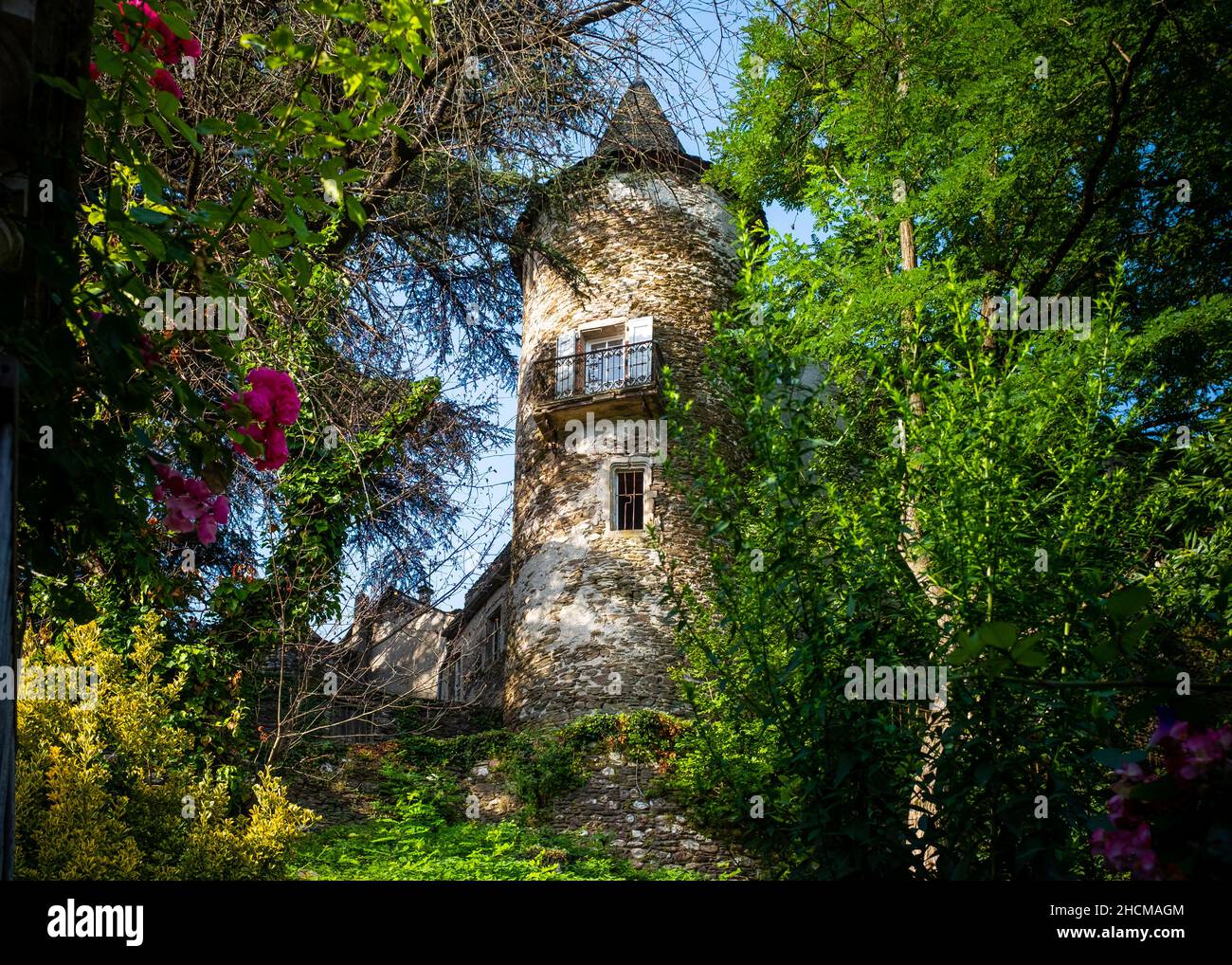 Torre de un castillo parcialmente destartalado visto a través del follaje en una pequeña ciudad del sur de Francia situada en las Cevennes, tomado en una mañana de verano soleado ingenio Foto de stock