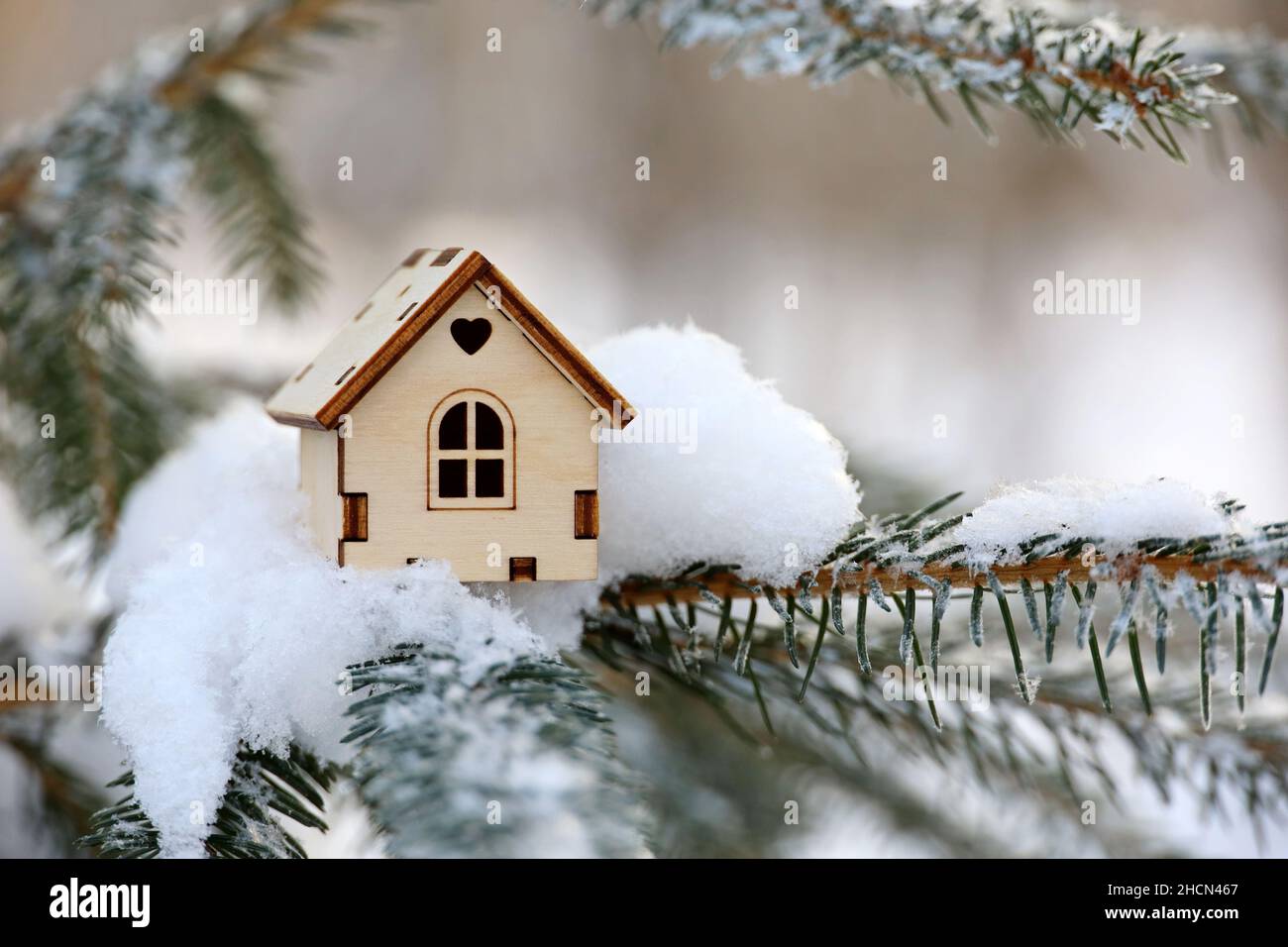 Modelo de casa de madera en una nieve sobre rama de abeto. Concepto de la venta de invierno de Año Nuevo, ganar la lotería de vivienda, bienes raíces en un área ecológicamente limpia Foto de stock