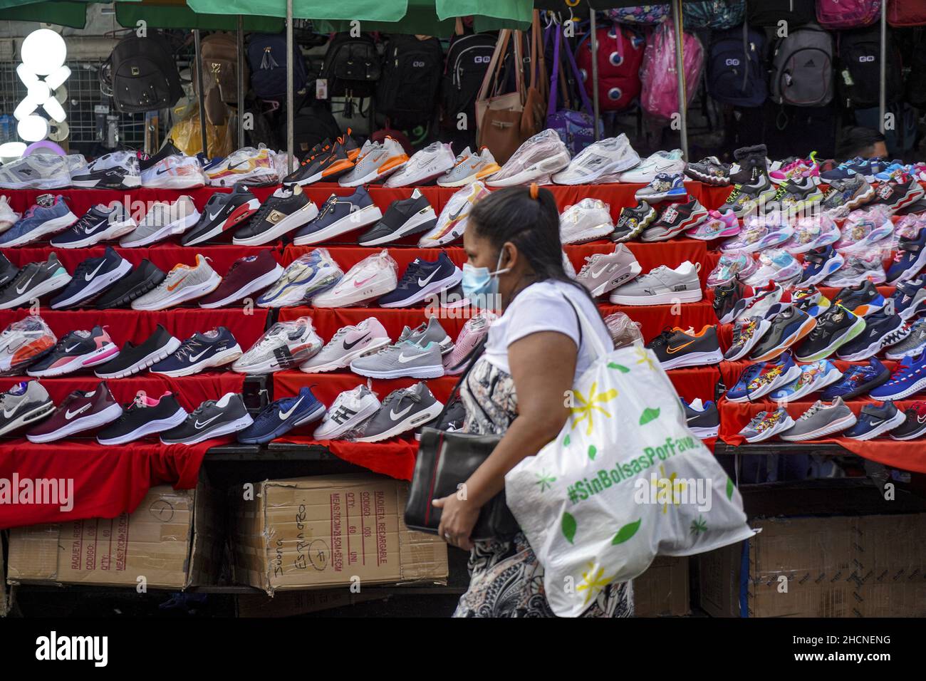 San Salvador, El Salvador. 30th de Dic de 2021. Una mujer pasa por una  tienda de zapatos en el mercado de la calle mientras la gente compra para  una noche de Año