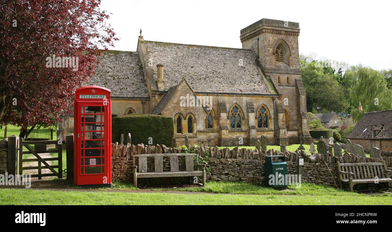 Snowshill pueblo Caja de teléfono roja en el pueblo verde con la iglesia Foto de stock