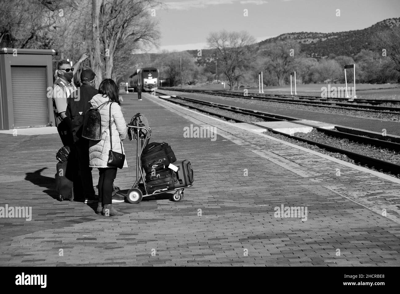 Los pasajeros se ponen de pie en la plataforma cuando un tren de pasajeros Amtrak (el Jefe del Suroeste) llega a la estación de tren en Lamy, Nuevo México. Foto de stock