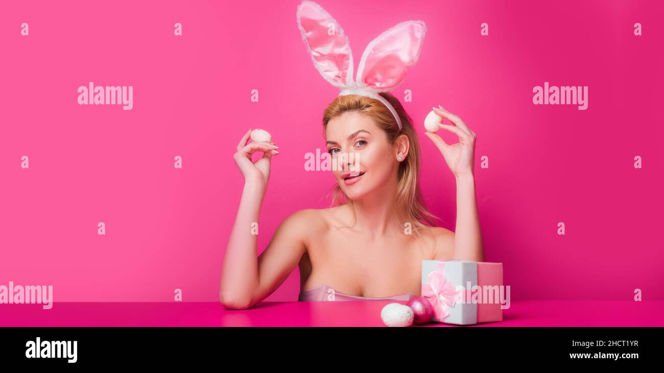 Bandera de Pascua con mujer conejita. Mujer con orejas de conejo mantener el huevo de pascua sobre fondo rosa. Foto de stock