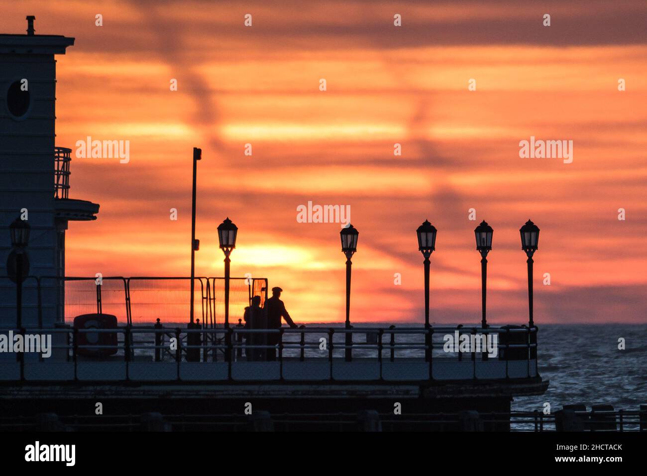 Worthing Beach, Worthing, Reino Unido. 1st de Ene de 2022. La gente está parada al final de Worthing Pier viendo como el sol se levanta sobre Worthing Pier el primer día de 2022. Foto de crédito: Julie Edwards/Alamy Live News Foto de stock