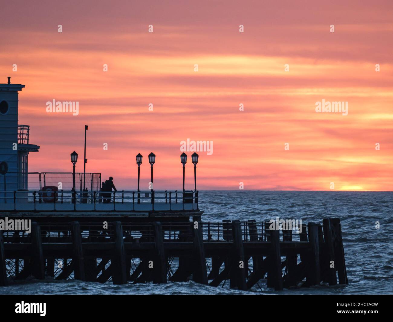 Worthing Beach, Worthing, Reino Unido. 1st de Ene de 2022. La gente está parada al final de Worthing Pier viendo como el sol se levanta sobre Worthing Pier el primer día de 2022. Foto de crédito: Julie Edwards/Alamy Live News Foto de stock