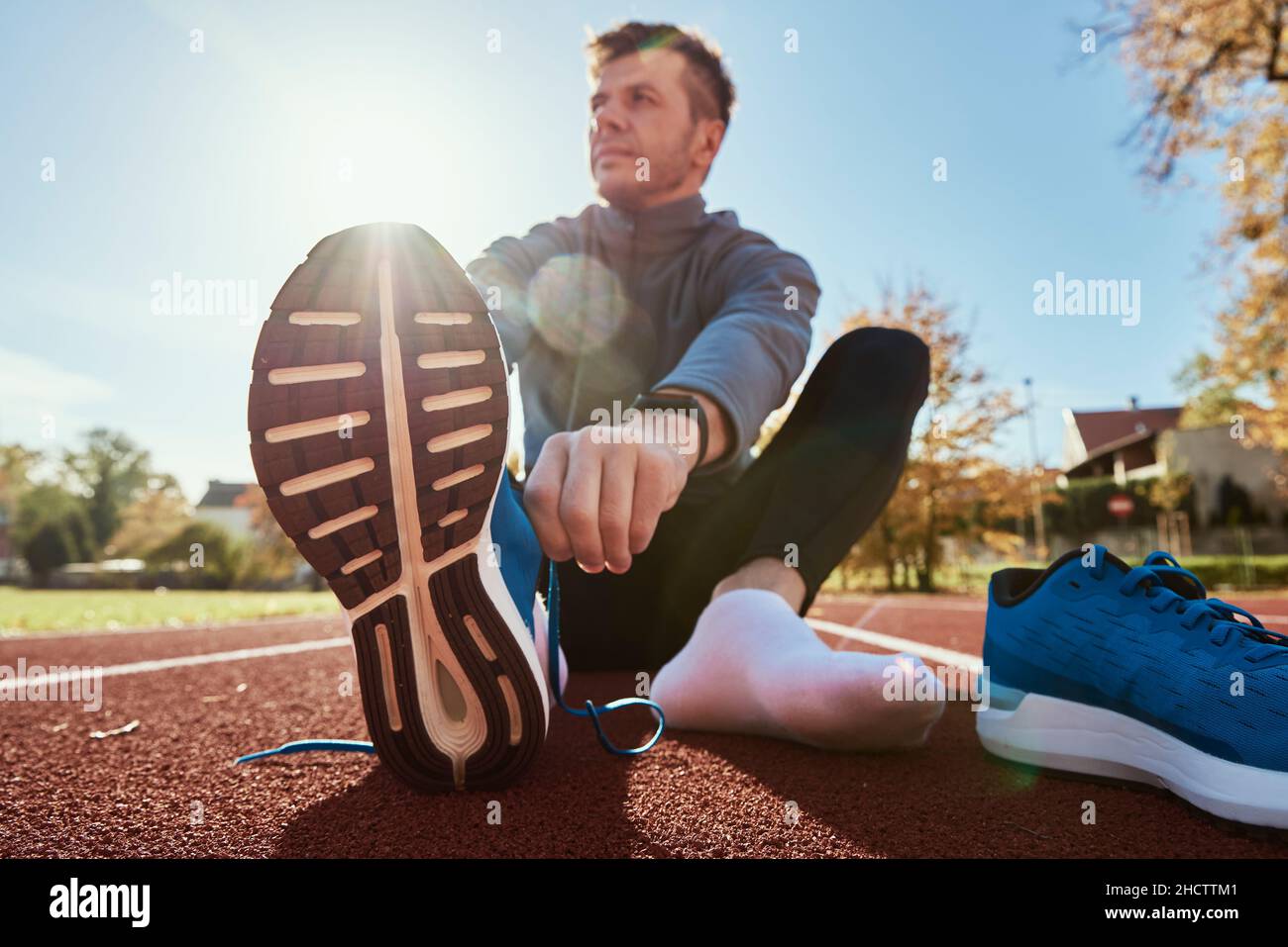 Las zapatillas de lona para hombre corredor en azul se preparan para correr en la pista estadio, en primer plano. Manos masculinas atadas en zapatillas deportivas para correr. Aptitud y vida