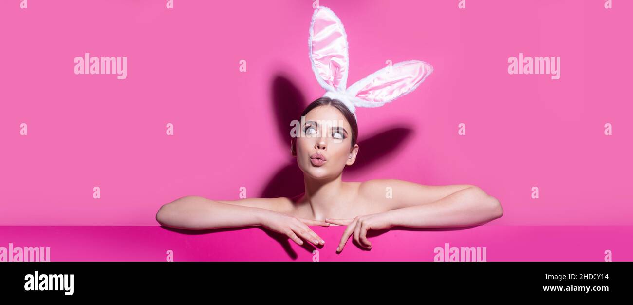 Bandera de Pascua con mujer conejita. Estudio de la joven de Pascua con orejas de conejito. Curioso aislado sobre rosa. Foto de stock