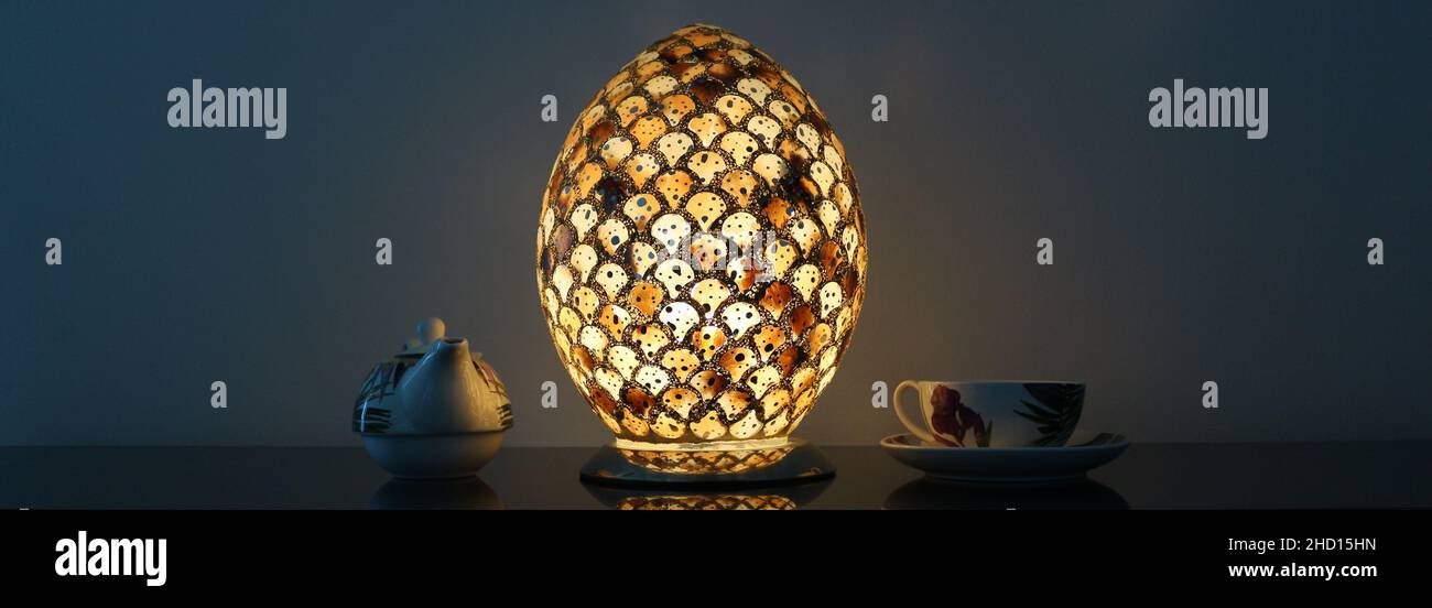 La luz de una lámpara ovalada que brilla y se refleja en una tetera y una tetera. Foto de stock