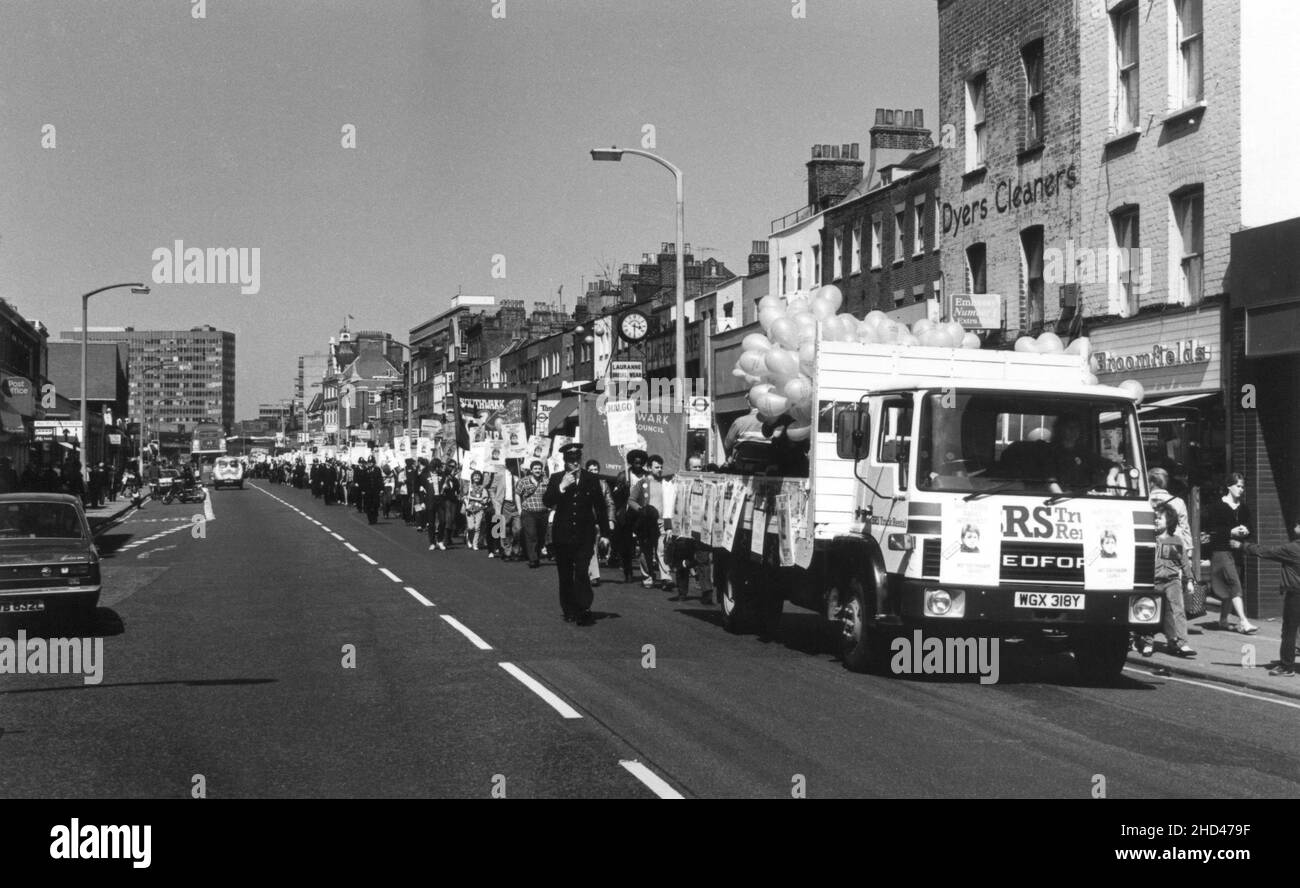 una marcha de manifestación por miembros de la rama Southwark del sindicato británico, NALGO (Asociación de Oficiales de Gobierno Nacional y Local) y el Consejo de Trades de Southwark, protestando contra el despido de un trabajador del Consejo de Borough de Southwark en Londres. Mediados de 1980s. La fotografía muestra a los manifestantes caminando por Walworth Road, Southwark, Londres. Los manifestantes siguen un camión flotando decorado con carteles y globos. Están llevando las pancartas del Consejo de Trades de Southwark Branch NALGO y Southwark, y pancartas con el eslogan “Who Cares About Workers? – No el Consejo Southwark”. Foto de stock