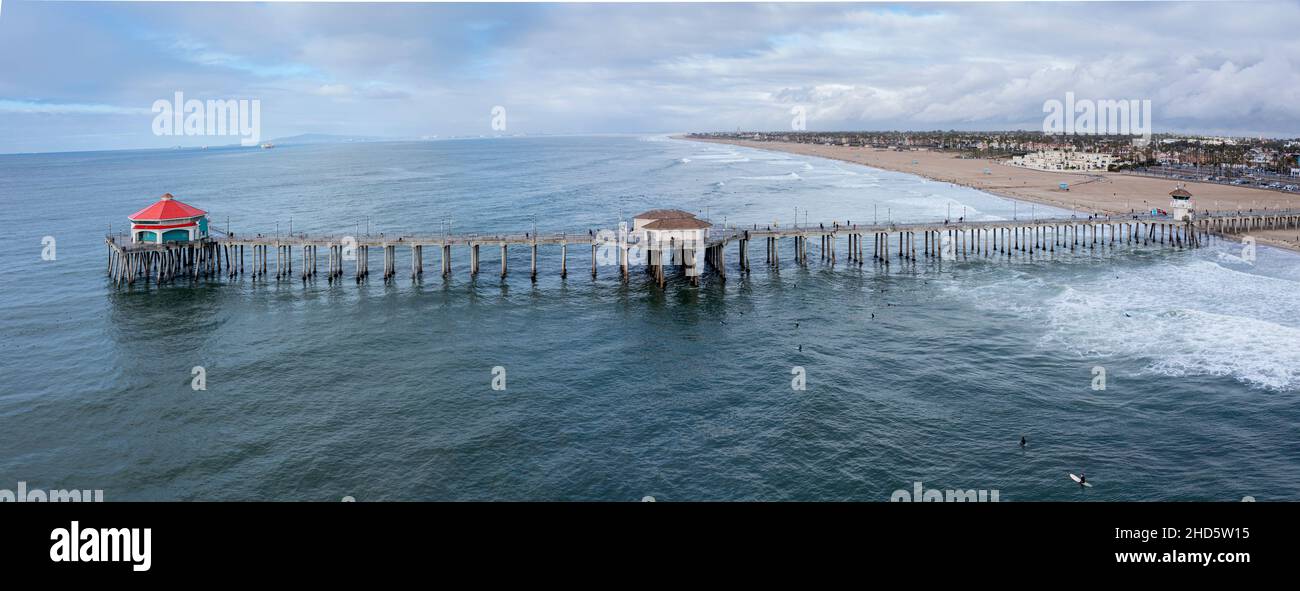 Vista aérea del famoso muelle de Huntington Beach en el condado de Orange, California, muestra la hermosa plataforma que sobresale sobre los marcos verdes y de agua fría de aga Foto de stock
