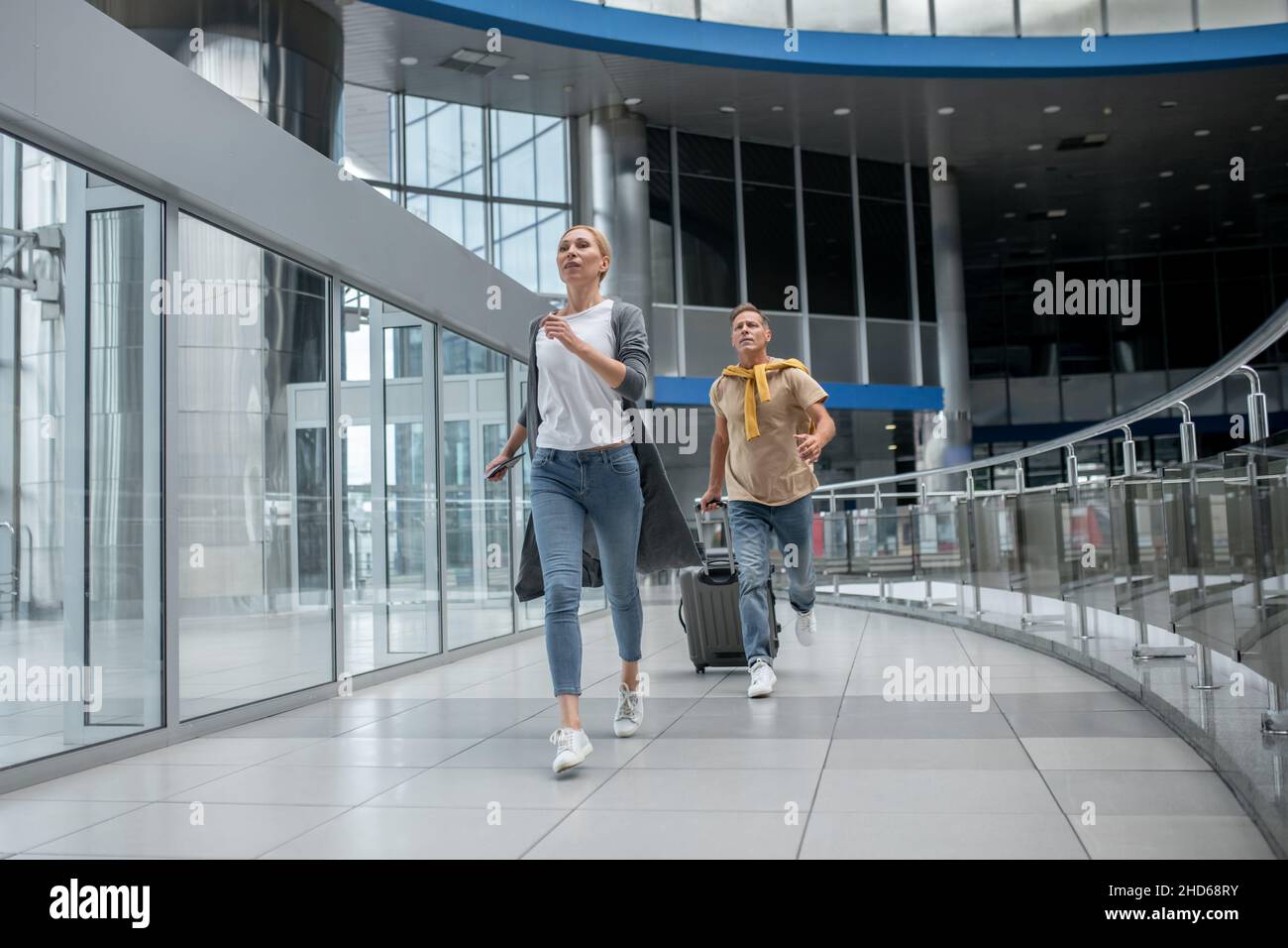 Dos pasajeros agitados corriendo a través de la terminal del aeropuerto Foto de stock