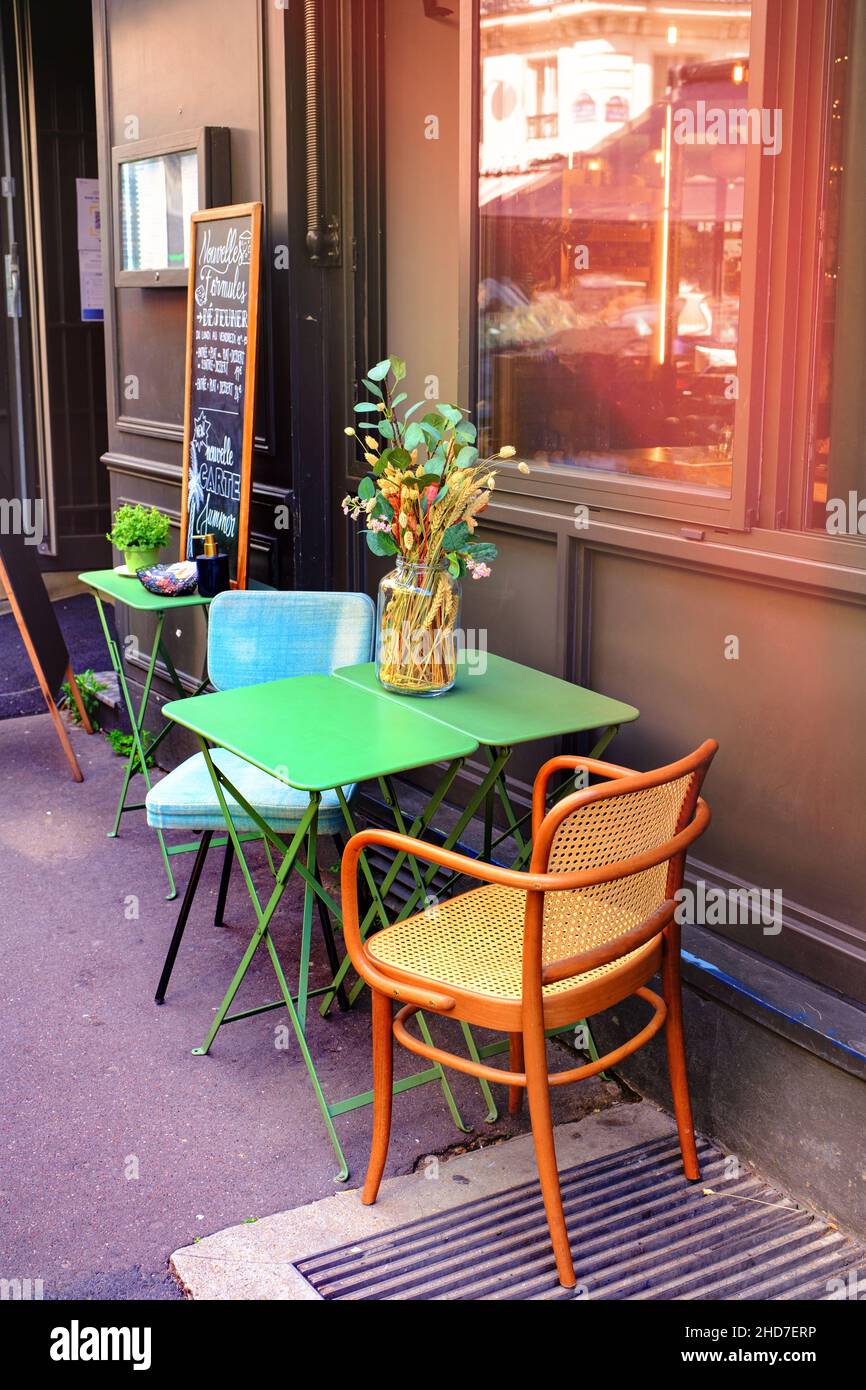 Pequeño restaurante francés - mesa y sillas decoradas con flores en la calle - París, Francia Foto de stock